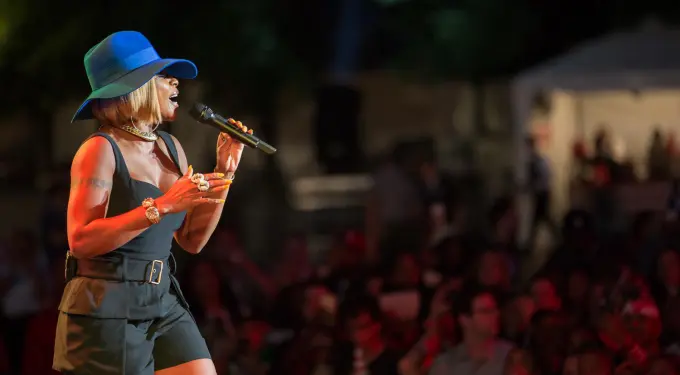 Mary J. Blige sings wearing blue hat and black outfit at concert