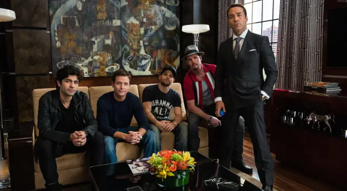 five men from Entourage posing in living room, one man holding blue object