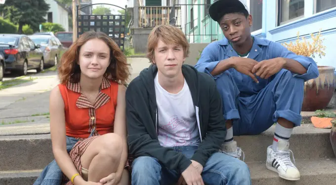 Three young people sit on steps in casual clothes outdoors