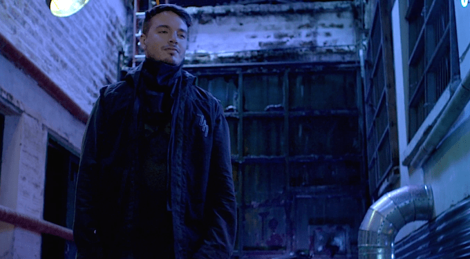 J Balvin stands in an alley under blue light in Ginza video
