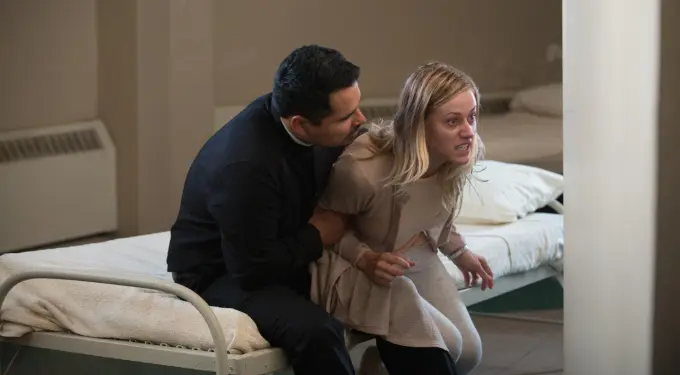 Man restrains angry woman sitting on bed in a tense scene