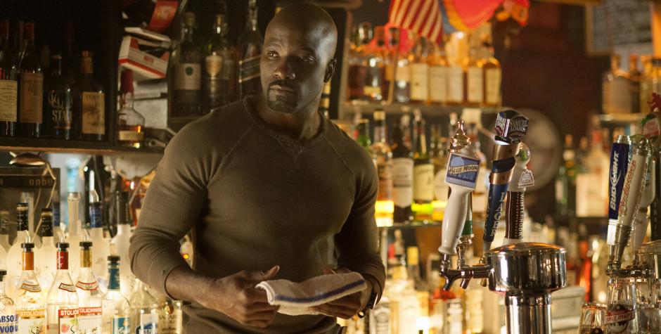 Man wipes bar counter with towel, surrounded by liquor bottles and beer taps