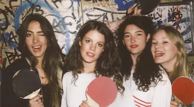 Four women from band Hinds holding ping pong paddles in front of graffiti