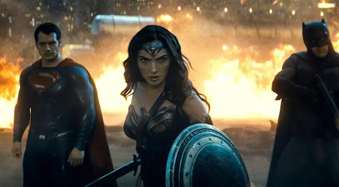 Wonder Woman with shield, flanked by Superman and Batman, fire behind