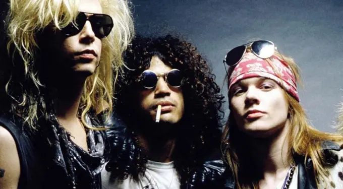 Three Guns N' Roses band members in sunglasses and 1980s rock style