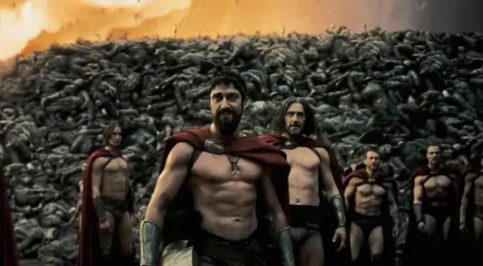 Spartan warriors in red capes stand in front of fallen enemies