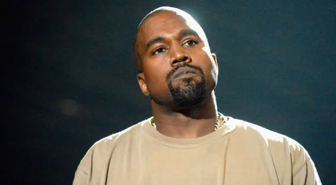 Close-up of Kanye West looking thoughtful against dark background