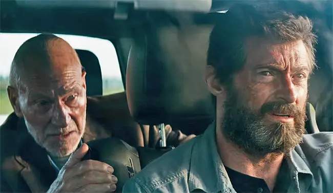 Older man talks to bearded man driving in car interior
