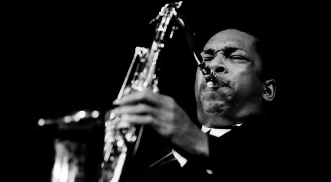 John Coltrane plays saxophone intensely in black and white photo