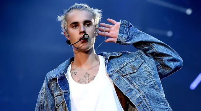 Justin Bieber performing on stage wearing denim jacket and white tank top