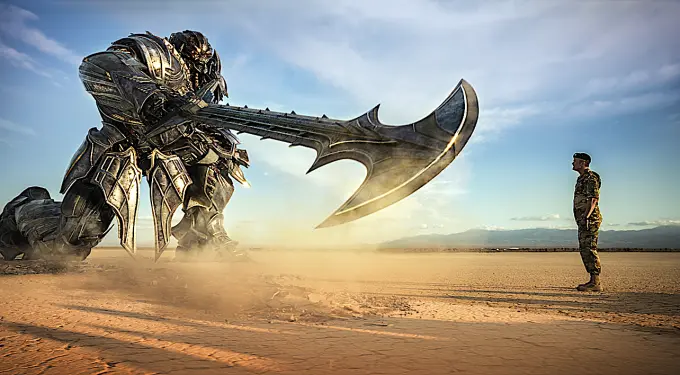 Transformer robot kneels with large axe facing soldier in desert