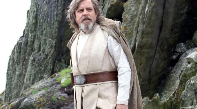 Luke Skywalker in Jedi robes standing outdoors on rocky cliff