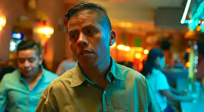 ‘En El Septimo Dia’ film scene featuring a man in a bar
Man in beige shirt looks serious in a crowded bar interior