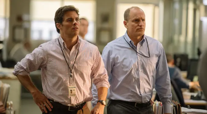 Scene from Shock and Awe showing two men working as reporters
Two men in office with press badges looking serious