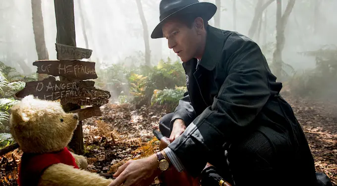 Scene from Disney’s “Christopher Robin” showing the character with Winnie the Pooh
Man in dark hat and coat reaches out to Winnie the Pooh teddy bear