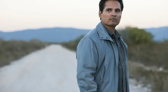Michael Peña in ‘Narcos: Mexico’
Michael Peña in blue jacket looks right on empty dirt road