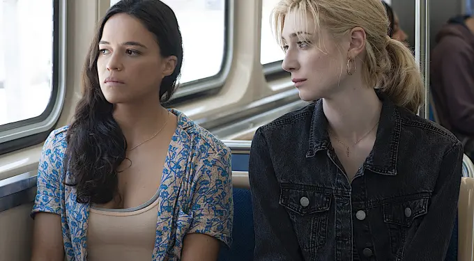 Two women sitting next to each other on train, both looking away