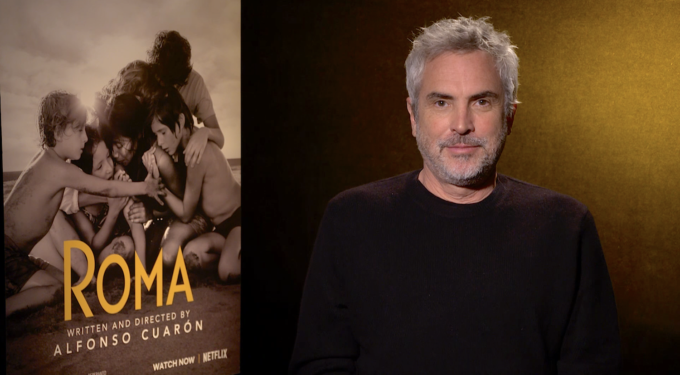 Mexican director Alfonso Cuarón beside ROMA movie poster in interview