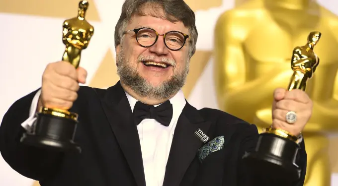 Mexican director Guillermo del Toro celebrates winning two Oscars.
Guillermo del Toro smiles holding two Oscars at awards event