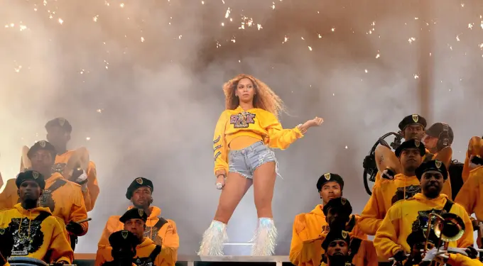 Beyoncé’s iconic 2018 Coachella ‘Homecoming’ performance captured live.
Beyoncé onstage in yellow sweatshirt and fringed boots at Coachella
