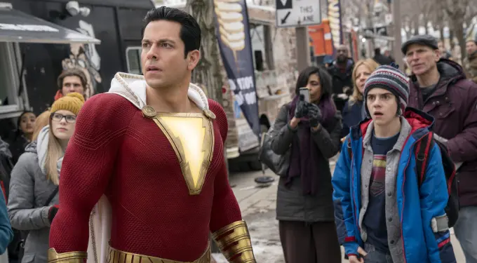 ‘Shazam’ character in costume surrounded by curious bystanders
Shazam in red suit stands alert as crowd watches on city street