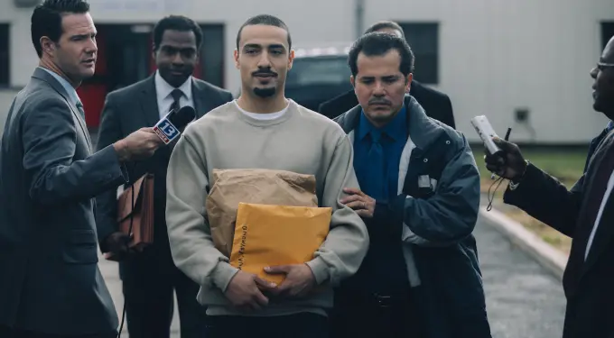 ‘When They See Us’ scene showing man arrested and interviewed by reporters
Man in handcuffs held by officer while reporters ask questions