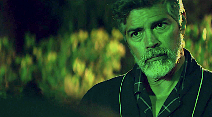 Esai Morales with beard looks serious in dark outdoor movie scene