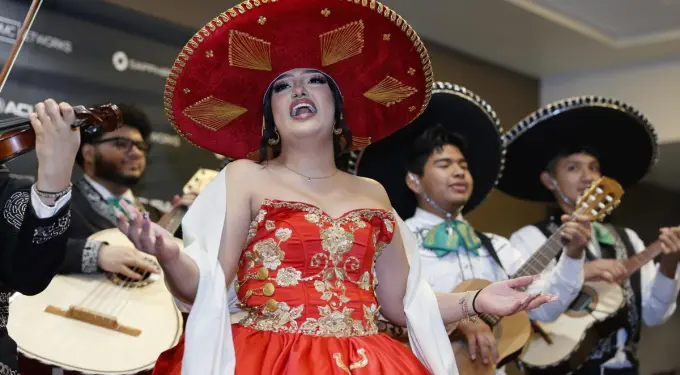 ‘Going Varsity in Mariachi’
Woman singing wearing red mariachi dress and hat with band