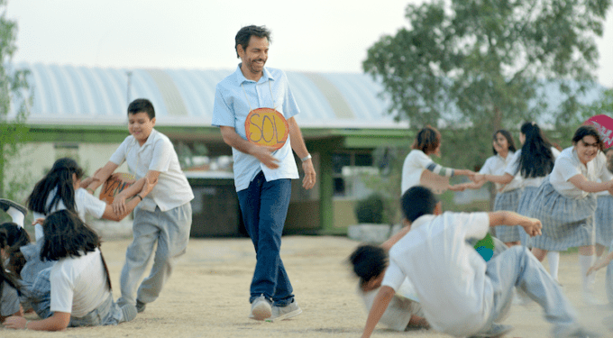 Eugenio Derbéz in ‘Radical’ (2023) at Sundance Film Festival
Eugenio Derbéz smiling with children playing outdoors in film scene