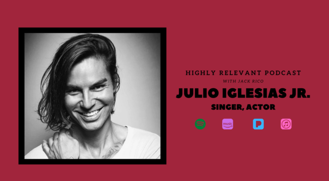 Black-and-white headshot of Julio Iglesias Jr. smiling with hand on chest