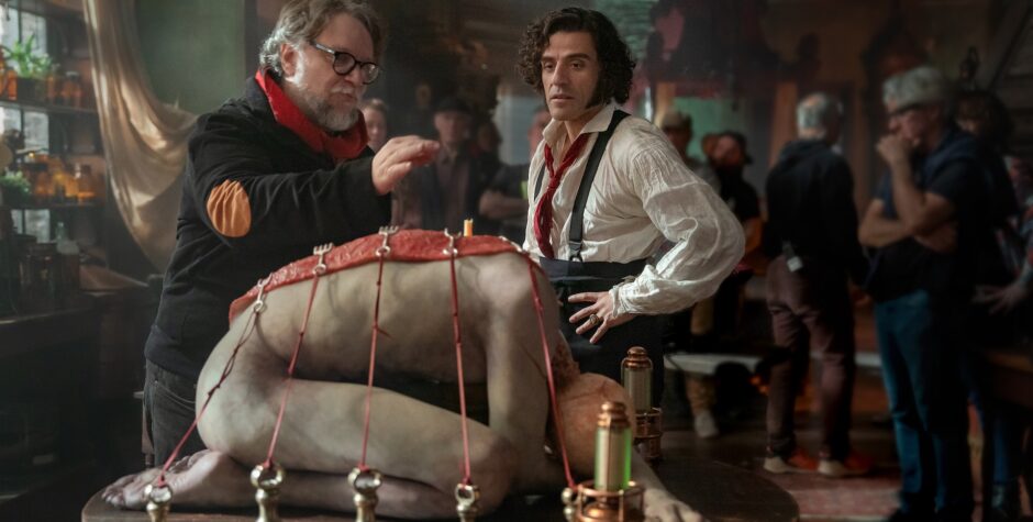 Guillermo del Toro directing Oscar Isaac on Frankenstein set with bound figure prop